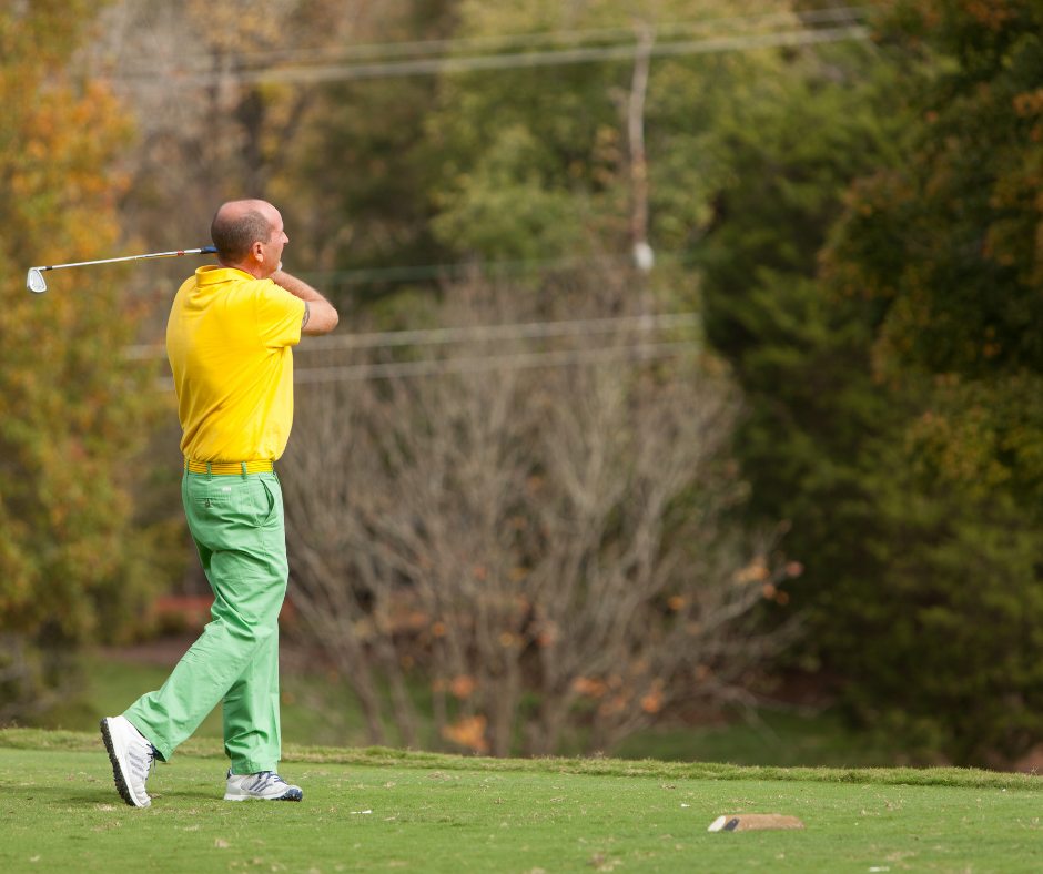 man swinging golf club on a course